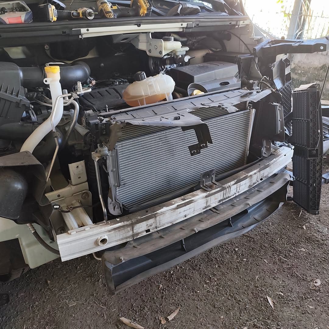 Face avant d'un Renault Trafic 3 ouverte, condenseur en cours de remplacement